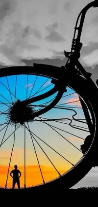 This phone live wallpaper showcases an artistic silhouette of a person standing by their bike