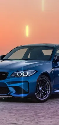This live wallpaper features a beautiful blue bmw parked on a beach during sunset