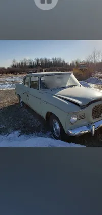 This old car parked in the snow live wallpaper is a must-have! The antique vehicle captures a look from the early 1960s and sits sparsely in a snowy landscape
