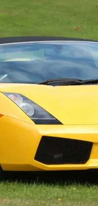 Looking for a stunning live wallpaper for your phone? Check out this vibrant yellow sports car parked on a green grass field! The Lamborghini style soft top convertible is brimming with immaculate detail, complete with bold styling and vibrant color that will add excitement to your screen