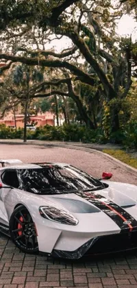 Get a stunning live wallpaper for your phone! The wallpaper showcases a white and red GT40 sports car parked on a brick road, with black steel and red trim