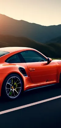 This phone live wallpaper features a red sports car, the Porsche 911 Turbo, driving on a road surrounded by mountains in the background