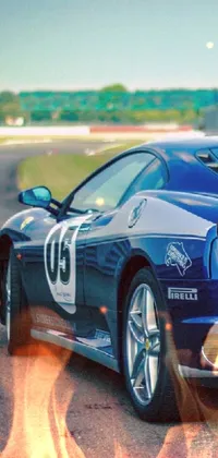 This mobile live wallpaper showcases a stunning blue sports car driving down a race track with an incredible speed