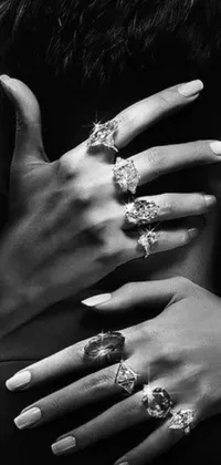This mobile wallpaper showcases a close up of beautifully decorated hands that are filled with designer LV jewelry and multiple rings