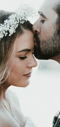This delightful live phone wallpaper depicts an intimate scene of a bearded man kissing a woman on the forehead