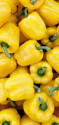 This live wallpaper features a stunning pile of yellow peppers arranged atop one another, surrounded by lush green plants
