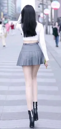 This phone live wallpaper features a stylish woman walking down a street wearing a skirt