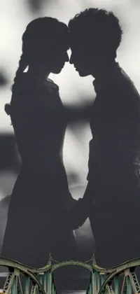This phone live wallpaper showcases a romantic black and white photograph featuring a couple closely standing on a bridge