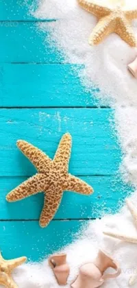 This phone live wallpaper features a wooden table topped with starfish and seashells, a nostalgic picture, and colorful emojis floating in a serene blue ocean background with sea foam
