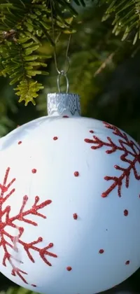 Looking for an eye-catching Christmas-themed phone wallpaper? Look no further than this exquisite design! Featuring a close-up shot of a red and white-colored ornament on a tree, this wallpaper delivers a unique paint-on-glass style that's sure to impress