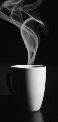 This HD phone live wallpaper features a steaming cup of coffee on a wooden table, accompanied by a black and white photograph sourced from a fine arts platform