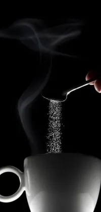 This eye-catching phone live wallpaper showcases a stunning digital rendering of someone pouring sugar into a steaming cup of coffee, set against a black and silver backdrop for a modern touch