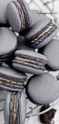 This live phone wallpaper features a bowl of delicious macarons sitting on a table in gunmetal grey, chocolate frosting, black white and purple