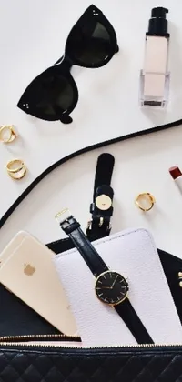 This phone live wallpaper features a black purse placed on a white table with gold accessories, captured in a flatlay style