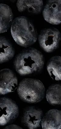 This digital wallpaper showcases a captivating close-up image of fresh blueberries amidst bullet holes on a black background