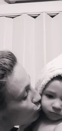 This phone live wallpaper features a captivating black-and-white photo of a woman kissing a baby, highlighting a precious moment between a mother and child