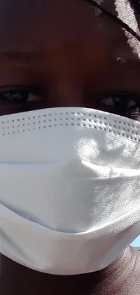 This phone live wallpaper showcases a detailed close-up view of a healthcare worker wearing a white face mask, with a focus on the mask's texture and their determined facial expression