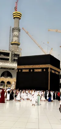 This mesmerizing <a href="/">phone live wallpaper</a> showcases a group of individuals standing near a building surrounded by hurufiyya with the imposing Ka&#39;bah in the background