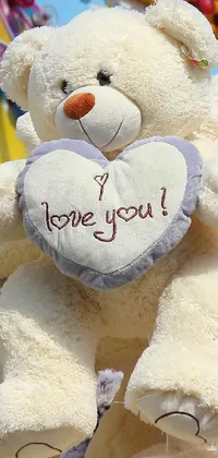 This live phone wallpaper depicts a charming white teddy bear holding a heart with "i love you" written in bold letters