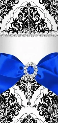 This phone live wallpaper boasts a classic black and white damask pattern adorned with a striking blue bow and embellished with ornate jewels and crystals