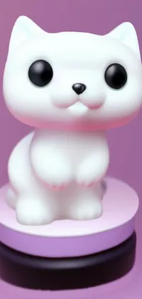 This phone live wallpaper features a hyper-realistic, kawaii white cat figurine sitting on a pink surface