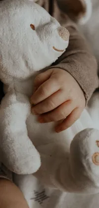 This adorable phone live wallpaper features an up-close shot of a baby tightly holding a stuffed animal