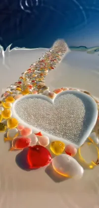 This phone live wallpaper features a beautiful heart made of sea glass on a serene beach