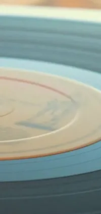 This phone live wallpaper showcases a stunning close-up of a vinyl record resting on a wooden table