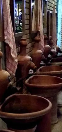 This live phone wallpaper depicts a row of clay pots against a rustic brick wall during early evening