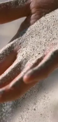 This phone live wallpaper depicts a hand holding a highly-detailed sand-stippled image, offering a mystical and ancient perspective