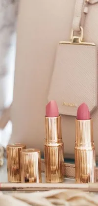 This stunning phone live wallpaper features a white purse and lipstick set against a table, decorated with a pink-gold color scheme