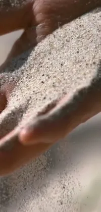 Enjoy the soothing beauty of a person holding fine sand in this stunning phone live wallpaper