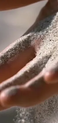 Looking for a soothing and calming phone live wallpaper? Check out this beautiful close-up shot captured at the perfect angle of sand held in someone's hands