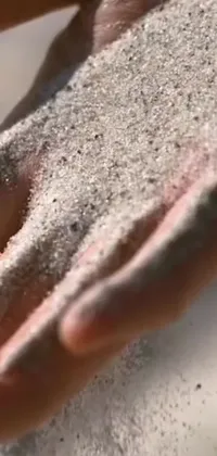 Looking for a stunning live wallpaper for your phone? Check out this beautiful option, featuring a close-up shot of hands holding sand