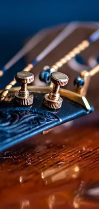 This live phone wallpaper showcases a detailed close-up shot of a guitar neck resting on a wooden table