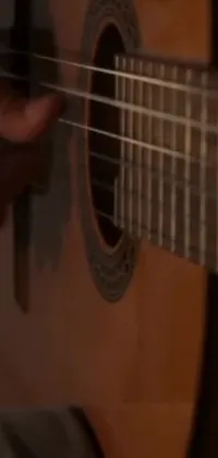 This stunning phone live wallpaper depicts a breathtaking close-up of a guitar being played by an anonymous musician