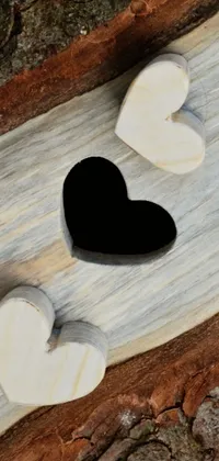 This live wallpaper depicts two hearts sitting on a rustic wooden surface