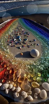 This live phone wallpaper showcases a serene beach with a rainbow of stones arranged in a beautiful glass sculpture-like formation